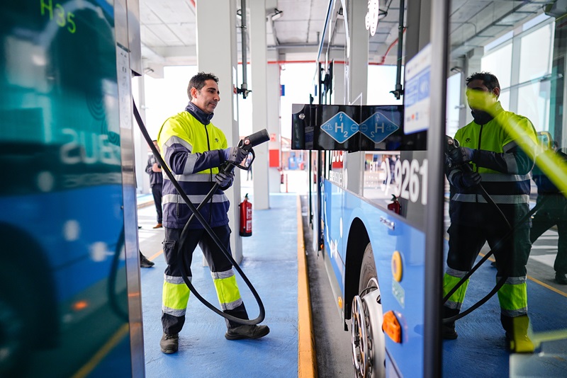 Un hito en la descarbonización del transporte
El Ayuntamiento de Madrid ha dado un paso histórico con la inauguración de la primera hidrogenera de autobuses de Europa, ubicada en el Centro de Operaciones de EMT Madrid en Entrevías. Esta instalación pionera refuerza el compromiso de la ciudad con la sostenibilidad y coloca a la capital como referente en el uso de tecnologías limpias en el transporte público.

Con una inversión total de 11,3 millones de euros, parcialmente financiada con fondos europeos FEDER, la hidrogenera cubre todo el ciclo del hidrógeno: producción, compresión, almacenamiento y distribución. Esta apuesta integral por el hidrógeno verde marca un antes y un después en la estrategia de descarbonización del transporte urbano en Madrid.

Hidrógeno verde como motor del cambio
La nueva hidrogenera, construida sobre una superficie de 49.618 m², es capaz de producir hidrógeno a partir de un proceso de electrólisis del agua, alimentado por 2.780 paneles fotovoltaicos que generan hasta 1,6 MWh de potencia. Este hidrógeno se utiliza para alimentar una flota inicial de diez autobuses cero emisiones, fabricados por la compañía portuguesa CaetanoBus.

Cada autobús cuenta con cinco botellas de almacenamiento de hidrógeno que garantizan una autonomía de 280 kilómetros o 20 horas de servicio continuo. Además, su tiempo de recarga es inferior a diez minutos, lo que asegura una operación eficiente y competitiva frente a otras tecnologías de transporte.

La instalación, desarrollada por EMT Madrid con tecnología nacional, incluye un electrolizador de tecnología PEM, tres tanques de almacenamiento y dos surtidores, todo diseñado para maximizar la eficiencia y reducir la huella ambiental del proceso. Con este proyecto, Madrid da un ejemplo claro de cómo integrar tecnología avanzada con infraestructuras sostenibles.

Más allá de una apuesta tecnológica
El proyecto no se limita al despliegue de infraestructuras. Forma parte de un plan estratégico más amplio que incluye la colaboración con el Centro Nacional del Hidrógeno (CNH2) para avanzar en la investigación y el desarrollo de tecnologías relacionadas con el hidrógeno.

Esta iniciativa, enmarcada dentro de la estrategia Madrid 360, busca alcanzar la meta de una flota 100 % sostenible para 2030, con autobuses que no emitan gases contaminantes. Además, Madrid continúa posicionándose como líder en políticas de movilidad sostenible, marcando un camino que otras ciudades europeas podrían seguir.

Una flota diseñada para la sostenibilidad
Los autobuses de hidrógeno incorporados a la flota de EMT Madrid destacan por su diseño avanzado y sostenible. Estos vehículos incluyen baterías tipo LTO de 43,8 kWh y cumplen con la norma de carrozado de la empresa municipal, asegurando la homogeneidad con el resto de la flota. Además, están equipados con espejos retrovisores con cámaras para mayor seguridad.

El coste de cada autobús asciende a 639.000 euros, de los cuales el 39,12 % está financiado por los fondos europeos NextGenerationEU. Esta inversión refleja un compromiso claro por parte de Madrid para liderar el cambio hacia un transporte público limpio y eficiente.

Innovación respaldada por experiencia
Aunque esta hidrogenera es un proyecto único en Europa, Madrid ya tiene experiencia con el hidrógeno como combustible alternativo. Entre 2002 y 2006, EMT Madrid participó en los proyectos europeos City Cell y HyFleet
, siendo pionera en España en la circulación de autobuses de pila de combustible.

Este nuevo proyecto no solo aprovecha la experiencia acumulada, sino que lleva la tecnología un paso más allá, integrando energías renovables y ampliando el alcance de su impacto positivo en el medio ambiente.

Un modelo para el futuro
La inauguración de la hidrogenera en Entrevías es mucho más que un logro técnico; es un símbolo de cómo las políticas públicas pueden impulsar un cambio transformador hacia un modelo de movilidad sostenible.

La tecnología de hidrógeno no solo reduce las emisiones contaminantes, sino que también crea un impacto positivo en la salud pública y en la calidad de vida de los ciudadanos. Este enfoque integral posiciona a Madrid como líder en innovación y sostenibilidad dentro de Europa.

Madrid 360 hacia un transporte sin emisiones
El transporte público sostenible es un eje fundamental del Plan Estratégico de EMT Madrid hasta 2025. La incorporación del hidrógeno verde se suma a otros proyectos de electrificación y eficiencia energética que buscan transformar el modelo de movilidad de la ciudad.

Con la meta de una flota cero emisiones para 2030, Madrid reafirma su compromiso con las políticas de transporte sostenible y con la lucha contra el cambio climático. La hidrogenera de Entrevías no solo es un hito tecnológico, sino también una declaración de intenciones para construir una ciudad más limpia y habitable.